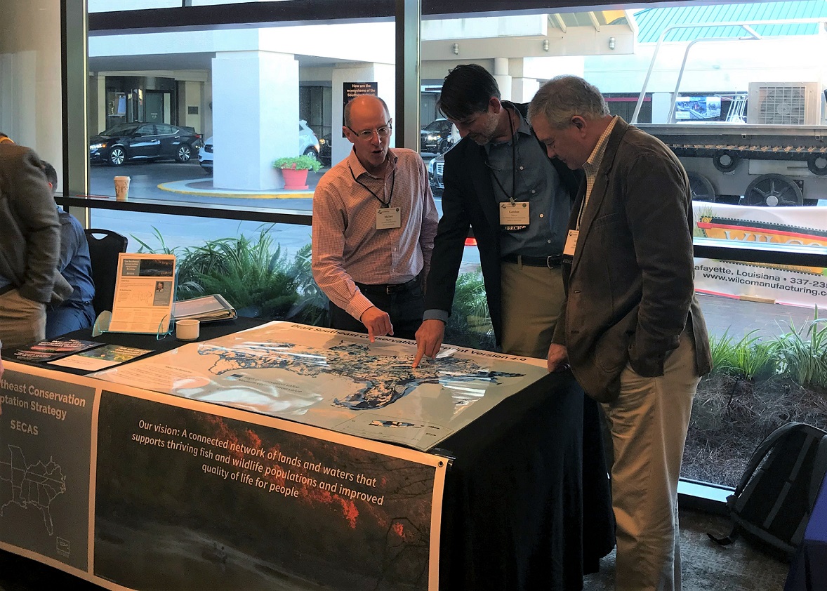 Gordon Myers and Ed Carter look at the map of Southeast Blueprint 4.0 at the SECAS exhibit booth.