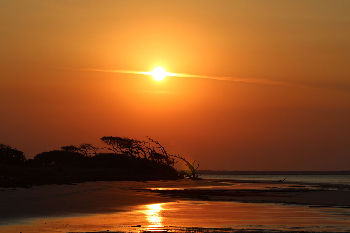 Photo of sun setting on a beach.