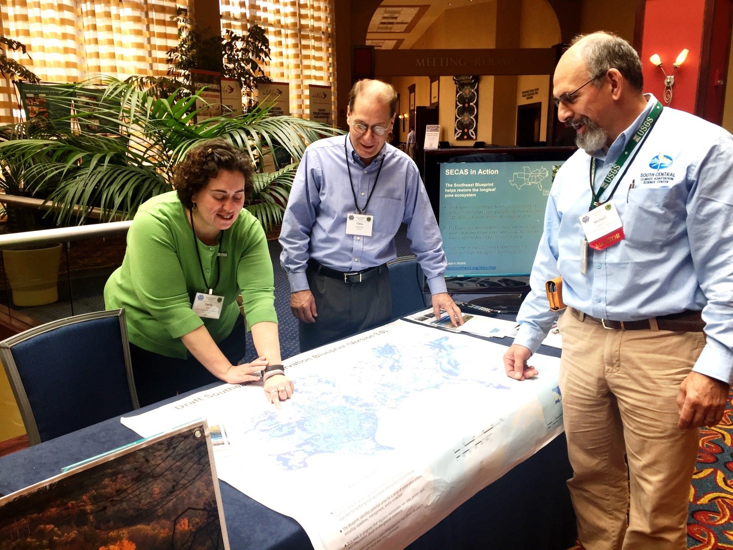 Three people gathered around a map of the Blueprint at the SECAS exhibit booth.