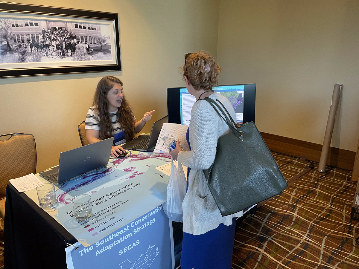 Brecken talks to a visitor at the booth